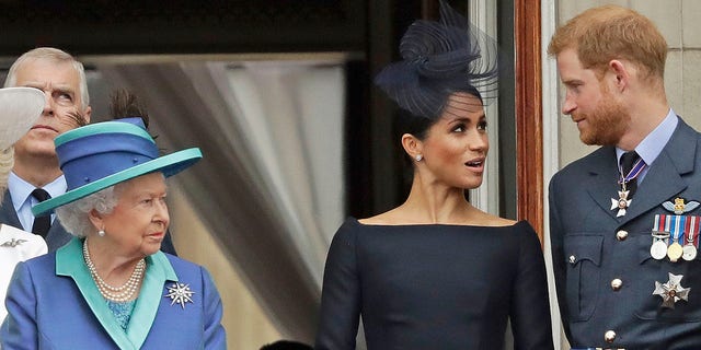 Königin Elizabeth, Meghan Markle und Prinz Harry stehen 2018 auf einem Balkon, um zu sehen, wie eine RAF über den Buckingham Palace fliegt.