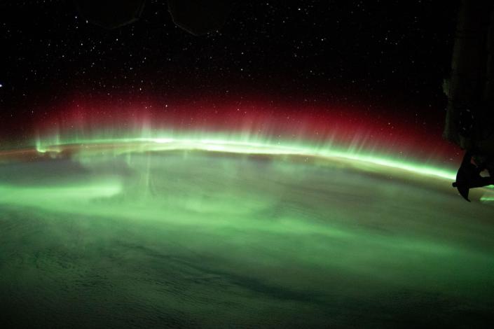 Grüne und rote Dämmerungslichter strömen über den Horizont der Erde gegen den schwarzen Raum
