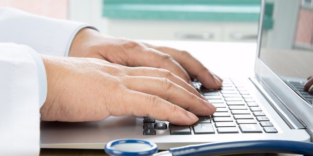 Nahaufnahme der Hand eines Arztes, der auf einem Computer tippt